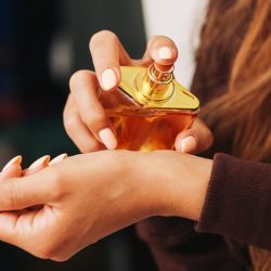 o persoana aplicand parfum pe piele