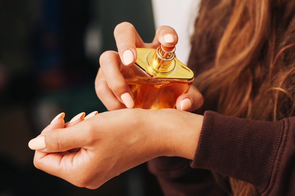 o persoana aplicand parfum pe piele